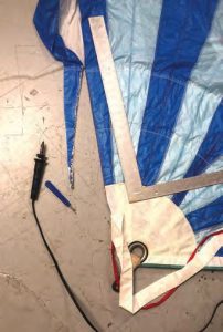 in the radial head area of the sail, John used a hot knife to remove multiple layers of reinforcing, with the seam acting as a guide.