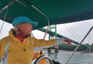 The author steers the boat as Ora Kali passes under the Deer Isle Bridge in Eggemoggin Reach.