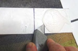 Drew slides a blade alongthe bond line. It’s critical to cut as close to
the line and as deeply as possible. Soak
with DeBond and wait 10 to 20 minutes,
repeating as needed.