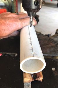 the author drilled holesinto the pipe before cutting it, using a piece of wood with a 90-degree groove cut into one side to stabilize the pipe.