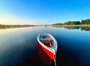 Gagetown at dawn. Our red dinghy, Heidi, rests in the foreground with a fishing boat in the distance