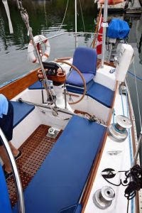 The traveler divides the cockpit. The rudder post/tiller head is just forward of the wheel and readily available should an emergency tiller be needed. Note the custom helm seat and tall coamings