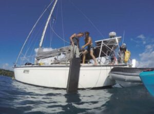 men pulling rudder from water