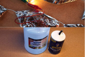 All that’s needed to create a homemade primary cell is vinegar, salt, aluminum, copper, and paper towels or cardboard, above. When connected in series, 19 of these cells will form a battery with enough power to light up a 12-volt, 25 LED bulb, at top of page.