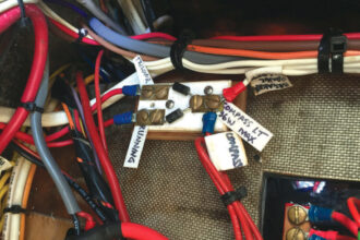 Under sail, John uses the masthead tricolor running light, but when motoring he must use the deck-level lights. The compass light is wired into both circuits so it turns on with either.