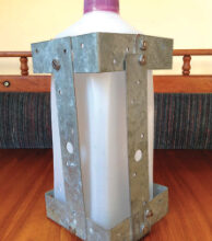 Milk is kept cold and accessible in this metal cage fashioned from galvanized tie straps and stainless-steel screws and nuts.