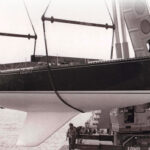 The moderately swept second generation of the C&C fin keel can be seen here on the C&C 61, Grampus, at her launching in Bronte, Ontario, in the mid-1970s, at top. Her builder, Erich Bruckmann, wearing a white windbreaker, is standing by the crane. C&C Yachts featured the distinctive hull profile with its highly swept keel in its sales literature, at left, which made it a little awkward to easily abandon this approach to keel design even after more effective shapes were developed.
