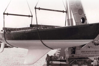 The moderately swept second generation of the C&C fin keel can be seen here on the C&C 61, Grampus, at her launching in Bronte, Ontario, in the mid-1970s, at top. Her builder, Erich Bruckmann, wearing a white windbreaker, is standing by the crane. C&C Yachts featured the distinctive hull profile with its highly swept keel in its sales literature, at left, which made it a little awkward to easily abandon this approach to keel design even after more effective shapes were developed.
