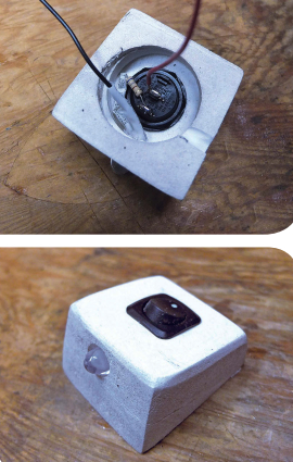 The large hole in the back of the lamp is deep enough to accommodate the nut on the base of the rocker switch as well as the wiring, at top. White heat-shrink tubing protects the connections to the LED to prevent short circuits. The LED is a press-fit in the housing and held firm with a drop of glue, above. Cliff chose the rocker switch for its low profile. He has not yet drilled the holes for the mounting screws, which will go through the thinner side of the block (see main photo).