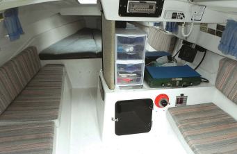 Under the flush deck, generous sitting headroom extends out to the hull. The fiberglass interior liner forms the bases for the settees and V-berth and includes a small counter with a sink and space for a portable stove, the battery switch, and the electrical panel. The daggerboard trunk is at the inboard side of the counter.