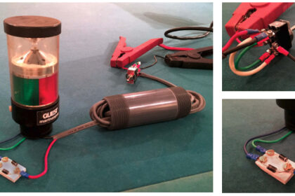 John made this model of his two-wires-into-three trick for demonstration purposes — he happened to have the Guest combination light lying around. The PVC tube represents the mast with the wires running through it, above left. One wire leads from the switch to the diodes, the other to the common return in the fixture. For this demo, John used colored wires for clarity, not to meet any code. The power supply is connected to the center tabs on the DPDT switch, upper right. The end tabs are cross connected so the polarity is opposite in the two “on” positions. Again, the wire colors are for clarity. The gray ends of the diodes point in opposite directions. The polarity of the wire at the common connection determines through which circuit electricity will flow. (The diodes could be arranged to fit inside some light fixtures.)