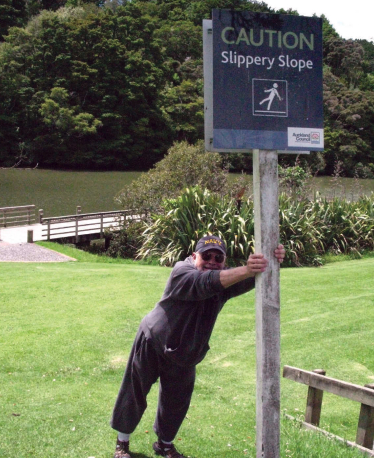Picture of someone leaning on a slippery slope sign
