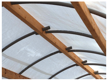 The bell ends of the conduit anchor the ribs at the center beam, at left. A typical rib starts at the center beam and bends over the top of the side beams, then passes down and through the gunwale track, below. The 2 x 4 spacer provides just the right clearance.