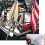 On small boats, storage space is at a premium, but with a little creativity you can still find a spot for a stern anchor, above. This lightweight Fortress has good holding power and is stored in a bracket mounted to the stern pulpit and just above the rolled-up rope-and-wood swim ladder. Stern rollers are mounted at the port and starboard rail corners, for use in anchoring, warping, docking, or when towing a drogue to slow down in heavy weather at sea. A 200-foot stern anchor rode is stored in a locker just aft of the tiller, at right. Jim cut the hole, epoxied the hook under the screw-on lid, and built a bulkhead underneath to contain the rode. This was previously unused space.