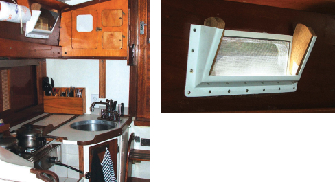 In Atelier’s galley, far left, the sink is original but that’s about all. The storage cabinet above the sink started as a way to cover the back of the depth sounder. Enough space was still available for two more smaller shelf units, now holding important necessities like onions and cat food cans. The design of the port, at left, is credited to Herreshoff, Cherubini, or Ralph Wiley (and probably others). These ports are usually made of wood, though the four DIY versions on Atelier are metal. They can hold a screen or a Plexiglas port or both at the same time. With the screen held tightly against the window frame, the plastic panel tilting toward the inside of the boat, and the wooden wedges between them holding both items in place, it’s possible to enjoy fresh air even when it’s raining.
