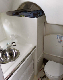 The compact head is tucked beside the companionway on the starboard side. It has a convenient grabrail on the vanity front and a fold-down seat for showering.