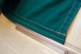 A boltrope on the leecloth slides into a track on the outboard edge of the bunk, so the leecloth is under the mattress and the sleeper.
