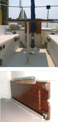 The forward end of the table is supported by a single aluminum leg, below. A female threaded insert in the table receives a male threaded fitting that is a press fit in the leg. A rubber foot protects the deck. Gary stores the folded table on the bulkhead of the starboard quarter berth, at bottom. The table leg clips into a plastic clamp on a 24-inch-long wooden bracket that holds the upper edge of the folded table.