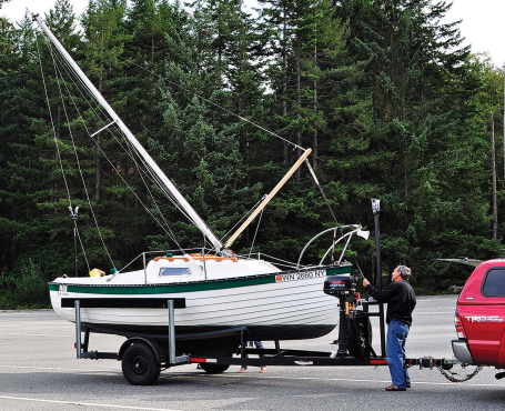 With the boom as a gin pole, Lenny Corin uses the mainsheet tackle to raise the mast by himself.