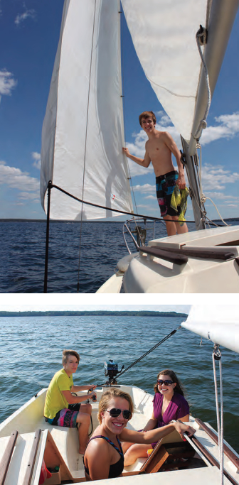 Conor enjoys the breeze funneling between the sails, at top, and takes the Sandpiper’s helm while Shannon and her friend LeeAnne enjoy the ride in balmy weather on Hamlin Lake.