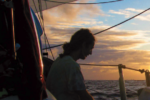 A man sitting on a boat at sunset