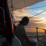 A man sitting on a boat at sunset