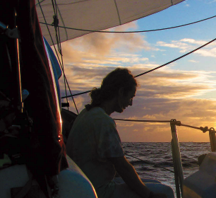 A man sitting on a boat at sunset