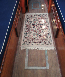 The cabin sole is solid teak planks over plywood, above. John leaves it unvarnished for ease of maintenance. The oriental rug is nice for bare feet.