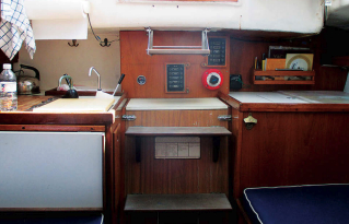 The galley is split aft with the icebox under a chart table. John modified the original icebox to add the chart table. The two-burner Origo stove is outboard of the sink on the starboard side.