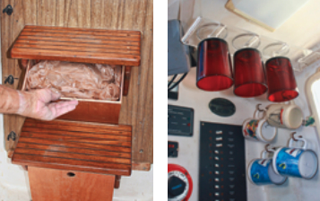 The trash container and liners occupy spaces under the companionway steps, at left. Hooks and acrylic racks hold mugs and glasses, at right.