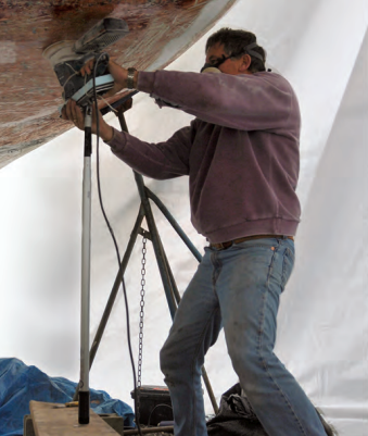 The adjustable boathook allowed Bert to sand the bottom, whatever height it was. A board laid across cinder blocks added flexibility to the arrangement.