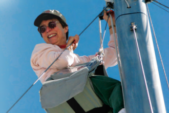 A woman climbing a boat mast