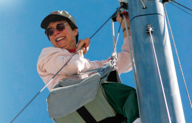 A woman climbing a boat mast