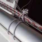 To fasten his rigging to the mast for trailering his boat, Allen passes the bungee loop around the mast and through itself, then forms a smaller loop to hold the rigging (visualize a figure eight). the finished tie-up holds the rigging away from the mast and reduces chafe.