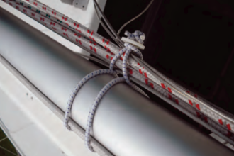 To fasten his rigging to the mast for trailering his boat, Allen passes the bungee loop around the mast and through itself, then forms a smaller loop to hold the rigging (visualize a figure eight). the finished tie-up holds the rigging away from the mast and reduces chafe.