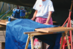 A woman sewing by a boat