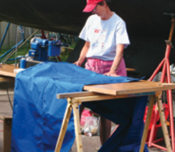 A woman sewing by a boat