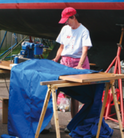 A woman sewing by a boat