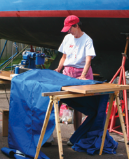 A woman sewing by a boat