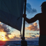 A silhouette of someone at sea during sunset