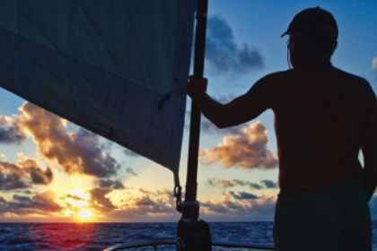 A silhouette of someone at sea during sunset