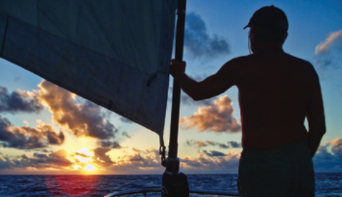 A silhouette of someone at sea during sunset