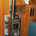 Burry’s diesel fireplace awaits the New York winter. The heat shield protects the bulkhead from heat given off by the flue all the way up to the headliner. The damper halfway up is needed for gusty winds.