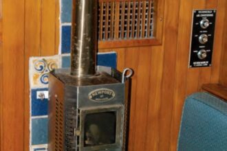Burry’s diesel fireplace awaits the New York winter. The heat shield protects the bulkhead from heat given off by the flue all the way up to the headliner. The damper halfway up is needed for gusty winds.