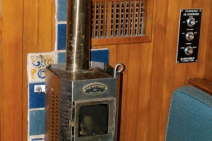 Burry’s diesel fireplace awaits the New York winter. The heat shield protects the bulkhead from heat given off by the flue all the way up to the headliner. The damper halfway up is needed for gusty winds.