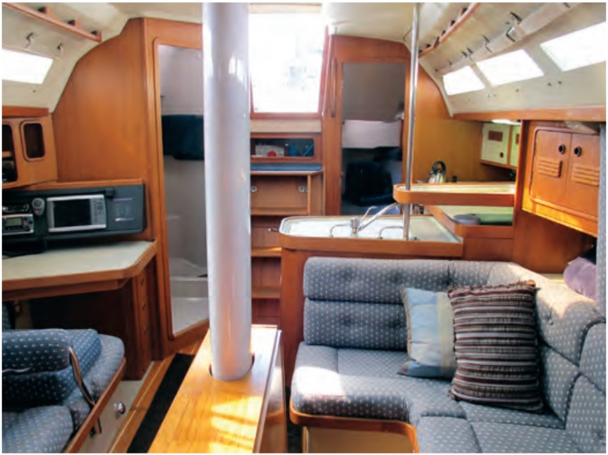 The nav station and head are to starboard of the tall companionway ladder and the dining table surrounds the keel-stepped mast.