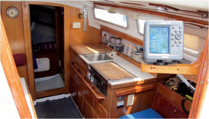 The starboard-side galley includes a two-burner stovetop, sink, drawers, lockers down low, and outboard stowage for sundry items. A common upgrade for do-it-yourselfers is a swing-out arm for critical instruments like a depth sounder and GPS.