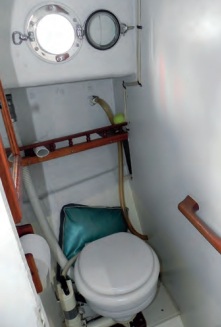 The head is enclosed. It has an opening portlight for ventilation and a well-placed handhold.