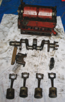 New pistons and the crankshaft with its freshly machined journals await assembly into the refurbished engine block.