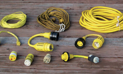 The contents of a typical shorepower bag, from left to right. Top row: cable-TV cord, telephone cord, 30A 125VAC power cord. Middle row: 30A 125VAC to 15A 125VAC adapter, 50A 125VAC to 30A 125VAC adapter, 50A 250/125VAC to 30A 125VAC adapter. Bottom row: polarity checker, 15A 125VAC to 30A 125VAC adapter, 30A 125VAC to 15A 125VAC adapter, 20A 125VAC to 30A 125VAC adapter. It’s a good idea to label the adapter with not only the type of socket it fits, but also with the name of your boat, so that on a marina dock there’s no question about who owns the adapter.